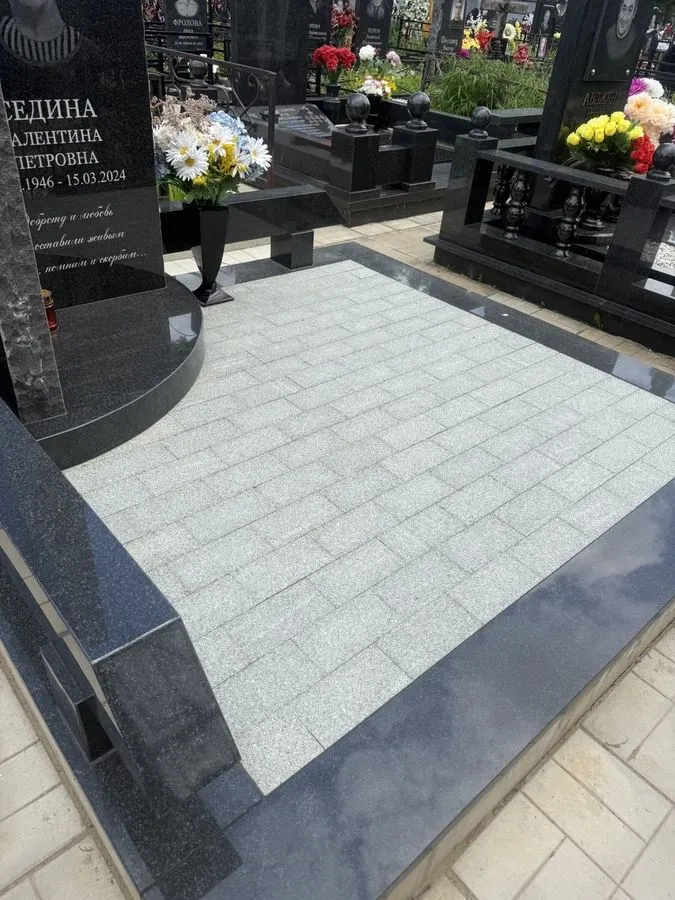 Участок захоронения, вымощенный серой гранитной плиткой